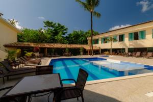 a swimming pool with chairs and a table next to a building at Miola Hotel in Porto Seguro