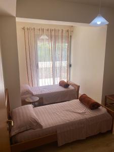 Duas camas num quarto com uma janela em Cactus Coastal: 3-Bedroom Condo II em Vlorë