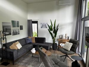 een woonkamer met een zwarte bank en stoelen bij Traum Ferienhaus mit Dachterrasse am Veluwemeer in Hulshorst