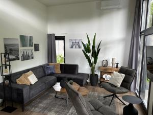 salon z czarną kanapą i krzesłami w obiekcie Traum Ferienhaus mit Dachterrasse am Veluwemeer w mieście Hulshorst