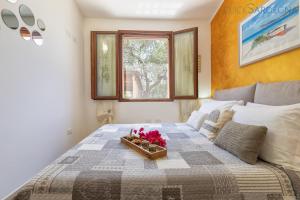 - une chambre avec un lit et un plateau de fleurs dans l'établissement ClickSardegna Villa Lavinia con piscina e accesso alla laguna Calich, à Casa Linari