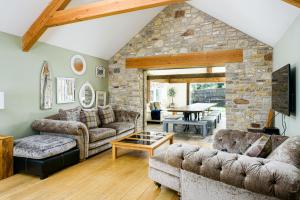 una sala de estar con sofás y una pared de piedra. en Bramley Barn near Bath + Hot tub en Siston