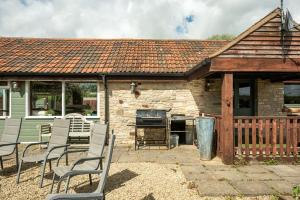 une terrasse avec des chaises et un barbecue en face d'une maison dans l'établissement Bramley Barn near Bath + Hot tub, à Siston