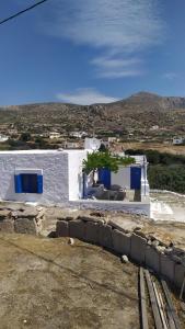 un bâtiment blanc avec des portes bleues et un arbre dans l'établissement Tinas House, à Afiartis