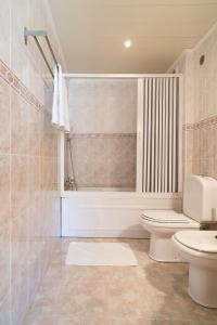 a bathroom with a toilet and a tub and a sink at Family Comfort House in Seixal