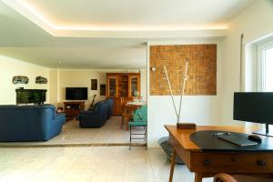 uma sala de estar com sofás azuis e uma televisão em Family Comfort House no Seixal