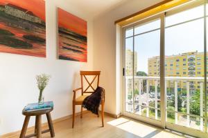 a living room with a large window and a chair at Family Comfort House in Seixal