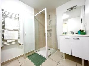 uma casa de banho branca com um chuveiro e um lavatório. em Lanester - Le Parc à bois - Wifi Fibre - Balcon - Parking privé em Lanester