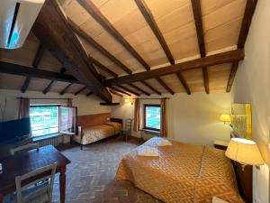 Un dormitorio con 2 camas y un escritorio en una habitación. en Hotel Relais Santa Genoveffa, en Paganico