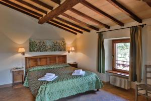 a bedroom with a bed with a green comforter and a window at Hotel Relais Santa Genoveffa in Paganico