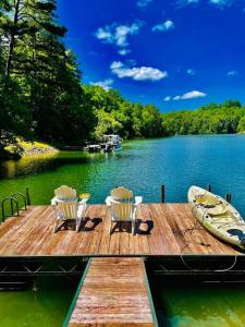 un muelle con 2 sillas y un barco en un lago en Stunning Lake front home with stunning decor, en Mill Spring