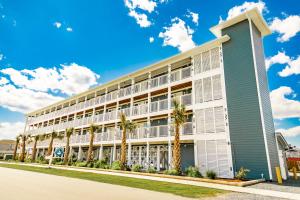 a large building with palm trees in front of it at Saltwater 106 1st Floor Low Tide in Surf City