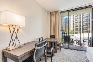 a hotel room with a desk and a balcony at CASTLE at Palms at Waikīkī in Honolulu