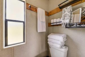 y baño con aseo, ventana y toallas. en Mayhill Tiny Home Vacation Rental with Covered Porch en Mayhill