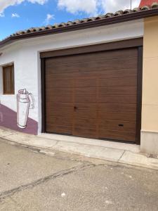 uma porta de garagem com uma pintura ao lado de uma casa em La Quesería em Villaherreros