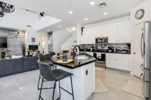 a kitchen with white cabinets and a counter with chairs at Goodyear Home with Heated Pool, Near Spring Training in Goodyear