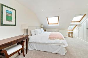 a bedroom with a bed and a desk and windows at Family Home near Clapham Common by UnderTheDoormat in London