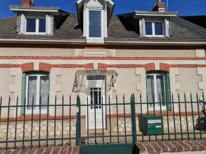 una valla verde frente a una casa en Grande maison de ville 120 m2 veranda et jardin., en Saint-Ouen
