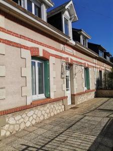 un edificio de ladrillo con ventanas verdes en una calle en Grande maison de ville 120 m2 veranda et jardin., en Saint-Ouen