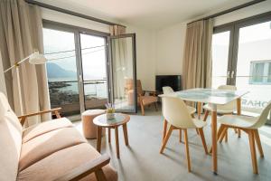 a living room with a couch and a table and chairs at Sandy feet relax suite in Kardamaina