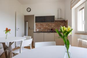 una cucina e una sala da pranzo con tavoli e sedie bianchi di B&B In Piazza a Mafalda Altre 20 foto