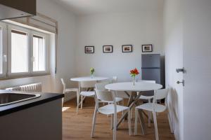 due tavoli in una cucina con sedie bianche e un frigorifero di B&B In Piazza a Mafalda