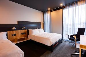 a hotel room with two beds and a desk at Alt Hotel Calgary University District in Calgary