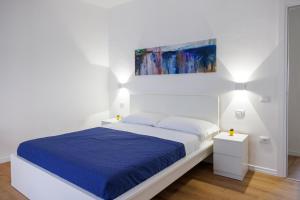 biała sypialnia z łóżkiem z niebieskim kocem w obiekcie B&B In Piazza w mieście Mafalda
