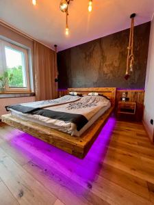 Schlafzimmer mit einem Holzbett mit lilafarbenen Lichtern in der Unterkunft Apartament Przy Parku in Muszyna