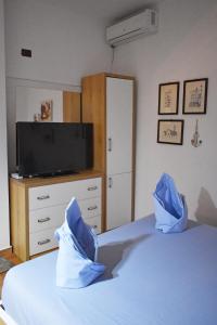 1 dormitorio con TV y 1 cama con almohadas azules en Sea Salt Studio Apartment, en Vlorë