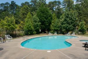 a large swimming pool with chairs and a table at Lake Oconee Abode with Patio, Grill and Fire Pit Table in Eatonton 