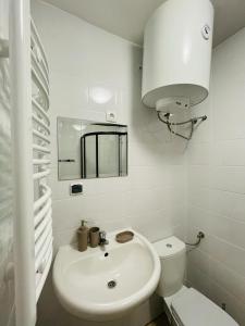 a white bathroom with a sink and a toilet at Apartamenty Cegiełka in Gąski