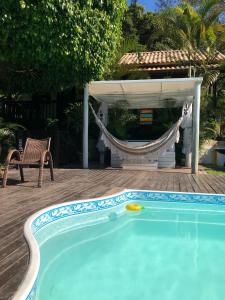 una piscina con una hamaca y un cenador en Pousada Aloha Beach House, en Praia do Rosa