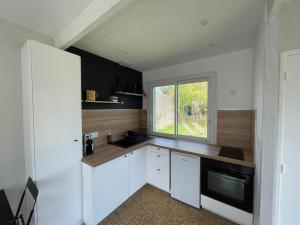 une cuisine avec des armoires blanches et une fenêtre dans l'établissement Les Lucioles Fort-Mahon Plage, à Fort-Mahon-Plage 16 autres photos