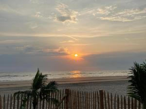- un coucher de soleil sur la plage avec une clôture en bois dans l'établissement Les Lucioles Fort-Mahon Plage, à Fort-Mahon-Plage