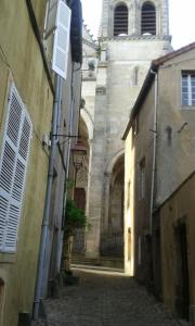 een steegje met een gebouw en een klokkentoren bij Chambre d'hôte au 3ème étage d'une maison de chanoine in Autun