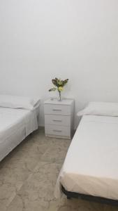 1 dormitorio con 2 camas y un jarrón de flores en una mesita de noche en Casa a 3 minutos del Casco y con facil aparcamiento- El rincón de Carmela, en Talavera de la Reina