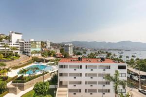 an apartment building with a swimming pool and a city at Departamento en Condominio Astoria in Acapulco