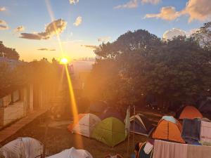 a group of tents with the sun setting in the background at Camping do Cid (no centro) in São Thomé das Letras