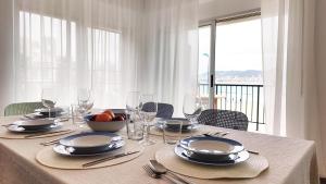 a table with plates and glasses and a bowl of fruit at PARRALUE Beach front home in Benidorm