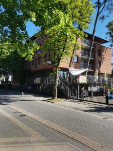 a person sitting on a bench on a street in front of a building at Apartament Planeta 110 Mielno in Mielno