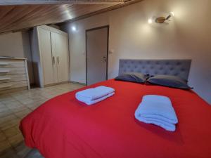 a large red bed with two white towels on it at Embrun Cosy in Embrun