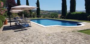 a swimming pool with an umbrella and a table and chairs at Case in campagna con piscina a Todi (monolocale) in Todi +6 photos