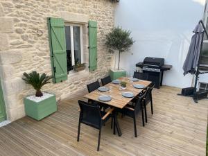 einen Holztisch und Stühle auf einer Terrasse in der Unterkunft Bella Vita Maison de charme au design soigné in Lorient