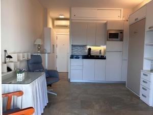 cocina y sala de estar con armarios blancos y mesa en ESTUDIO PORTAMAR, en Almuñécar