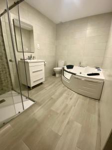 uma casa de banho com uma banheira, um lavatório e um WC. em Casa SobreMonte em Muxía