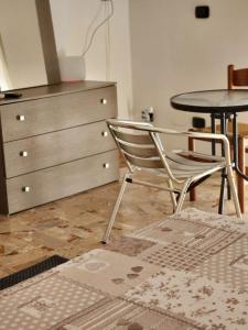 uma cadeira e uma mesa num quarto com uma cómoda em Sicily Guest House em Gela