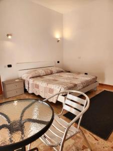 a bedroom with a bed and a glass table and chair at Sicily Guest House in Gela