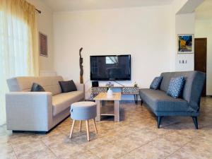 a living room with two couches and a tv at Almyriki Apartment in Ierissos