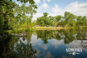 a man is sitting in a boat on a lake at Tentrr State Park Site - Nebraska Louisville SRA - Riverview D - Single Camp 